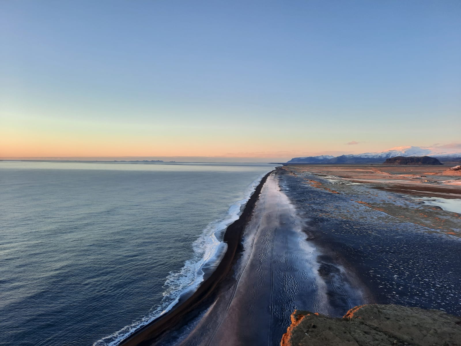 En mörk strand där hav och land möts